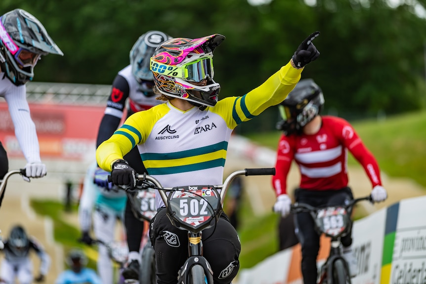 Josh Jolly points at the crowd. He's wearing BMX riding gear and a helmet