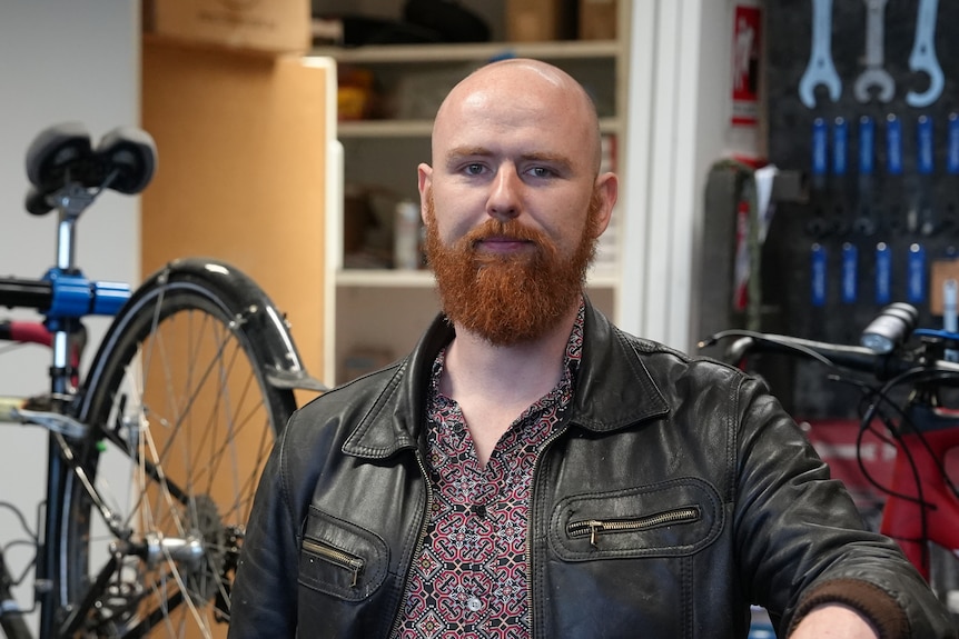 A man stands in front of a bike and tools.