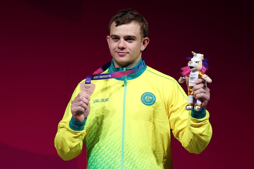 Ollie Saxton holds a bronze medal.
