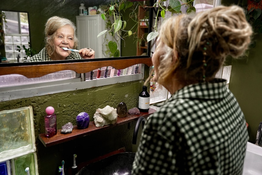 A woman brushes her teeth in the mirror