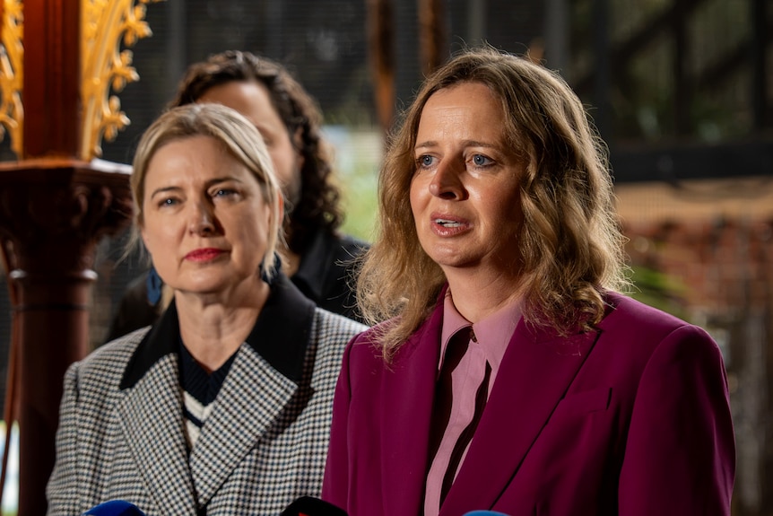 Minister Emily Bourke looks at the camera with Adelaide Zoon int he background. She is wearing a marron jacket