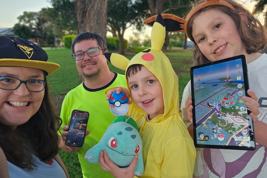 A family with pokemon merchandise in a park