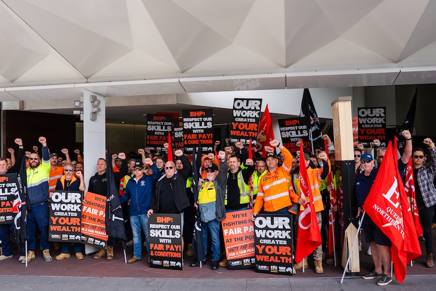 A group photo of men in uniforms with signs saying 'our wealth your health'.