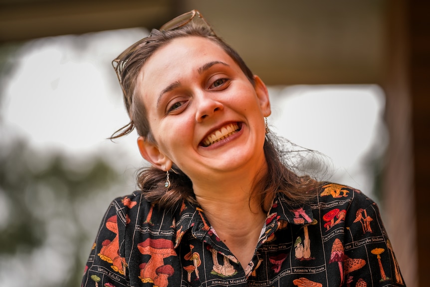 A woman in a colourful shirt smiling