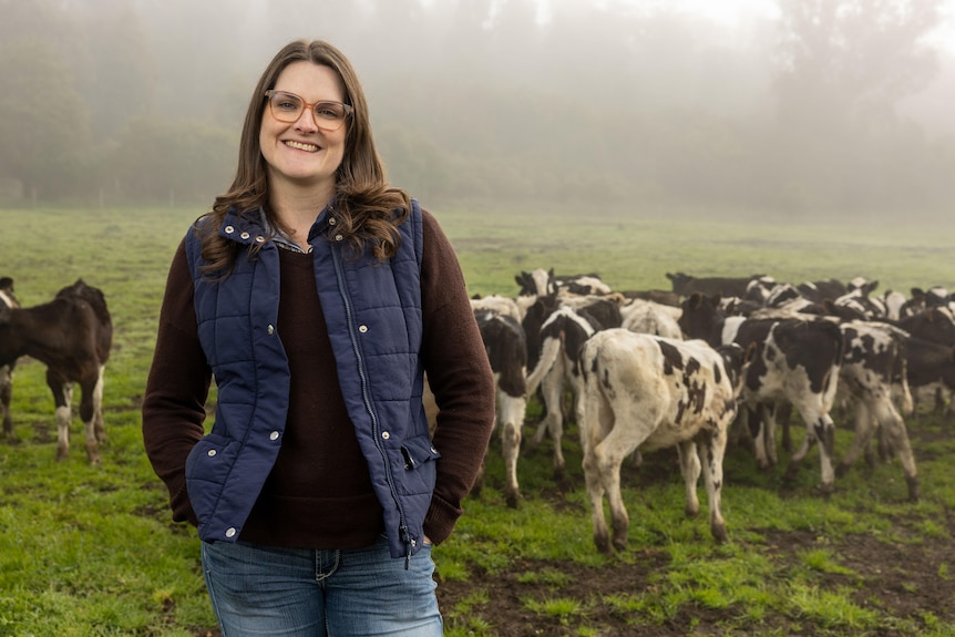 Bec stands infront of a mob of dairy cows, it's a foggy day behind her