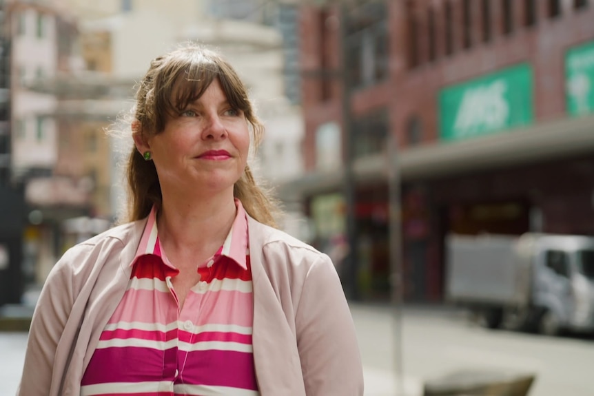 posed shot of woman in street looking to right of pic.