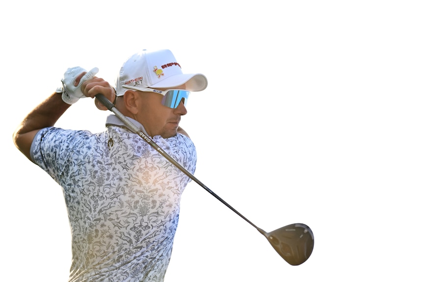 A man swings a golf driver.