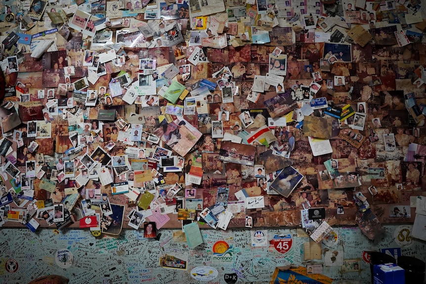 A wall inside a hotel is plastered with photos, signatures, business cards, plane tickets and other mementos left my travellers.