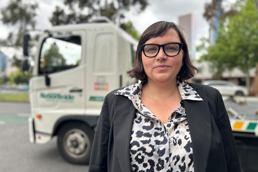 Erin Turner stands in front of a tow truck. 