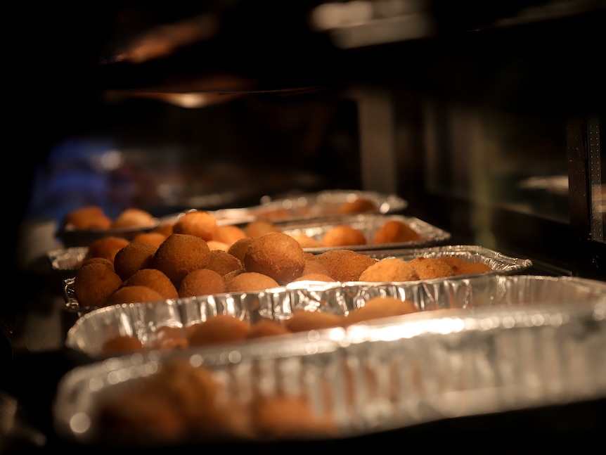 Trays of fried cheese balls in a bain mairie under a warming light