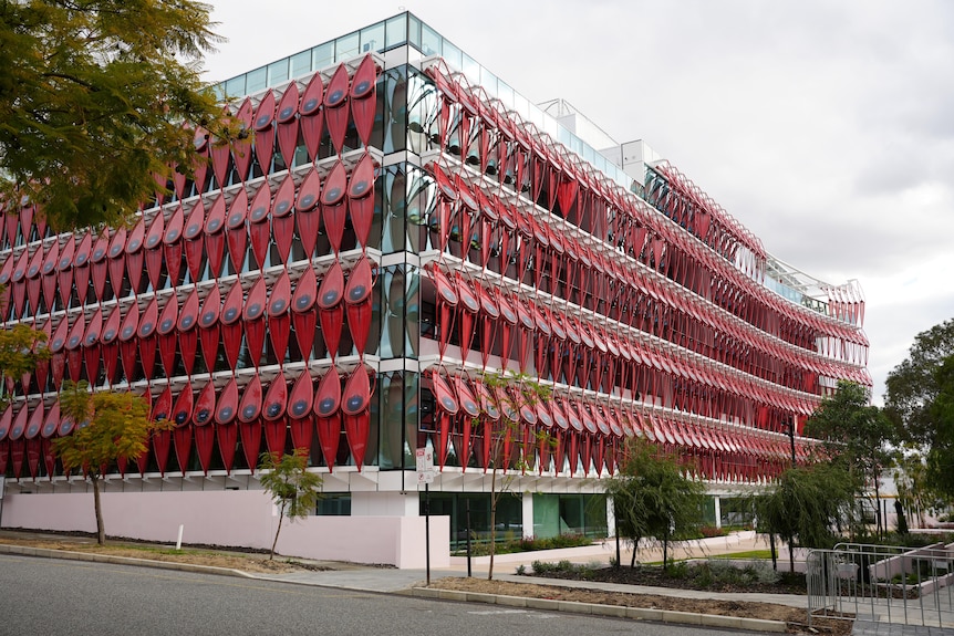 An office building with a facade comprising red metal sturt peas