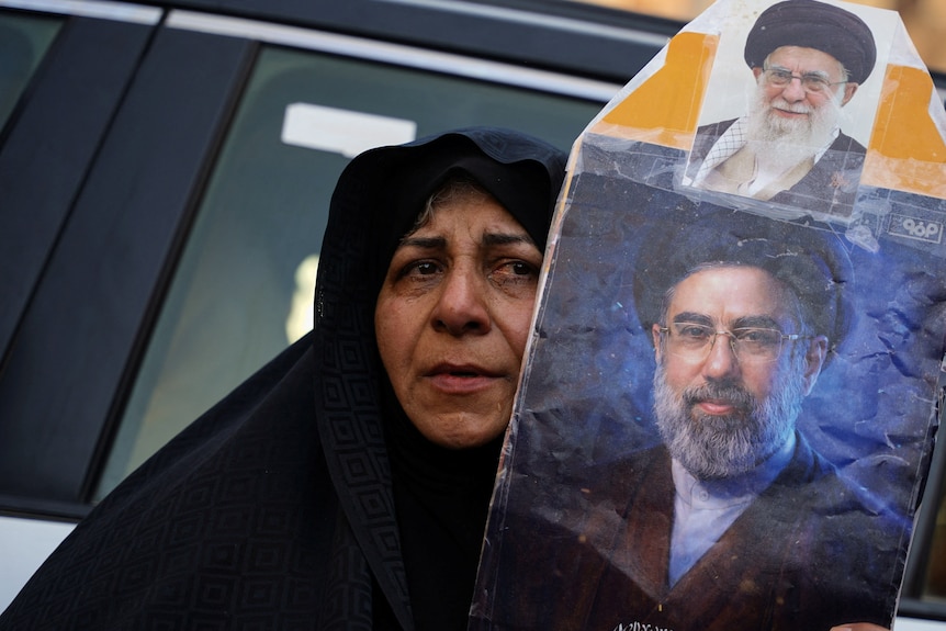 A woman holds a portrait of Iran's Supreme Leader Mojtaba Khamenei and Iran’s late Supreme Leader Ayatollah Ali Khamenei.