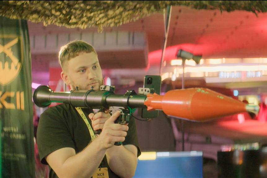 A man holding a replica rocket launcher over his shoulder.