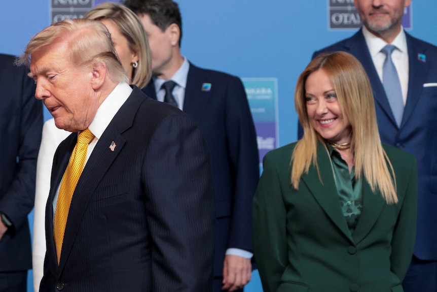 U.S. President Donald Trump walks past Italy's Prime Minister Giorgia Meloni at a NATO summit.