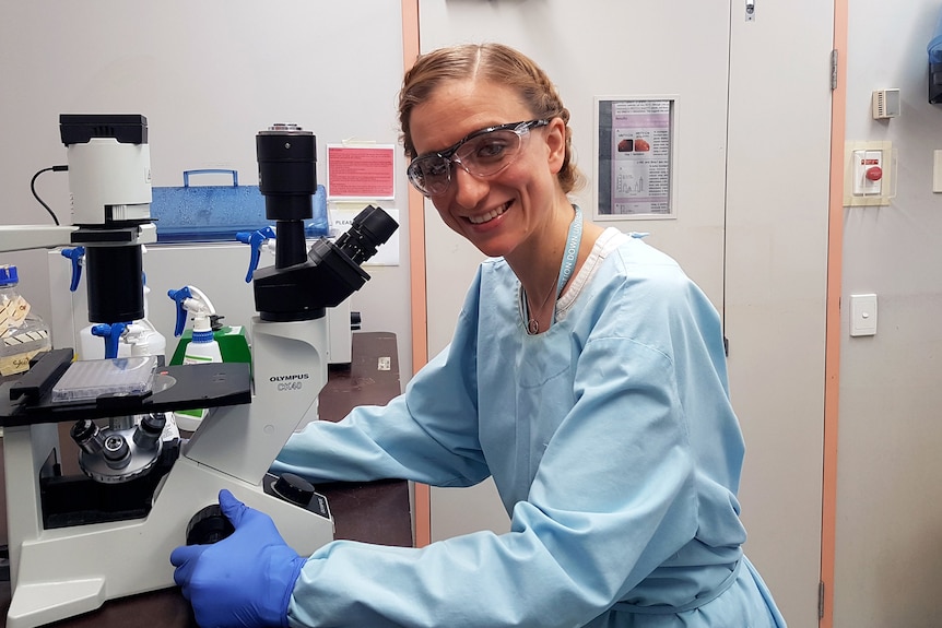 woman in science coat looking at microscope