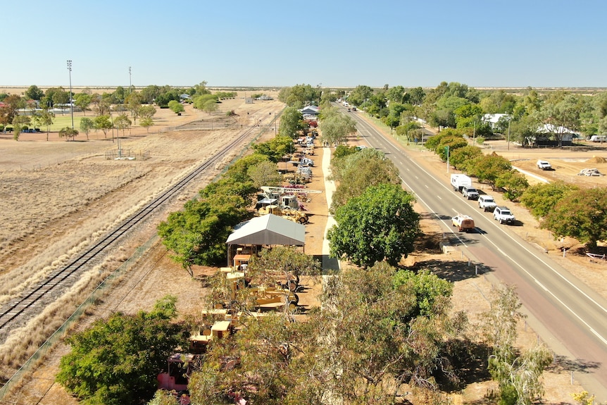 drone view of town, with line of trucks between a railway and road