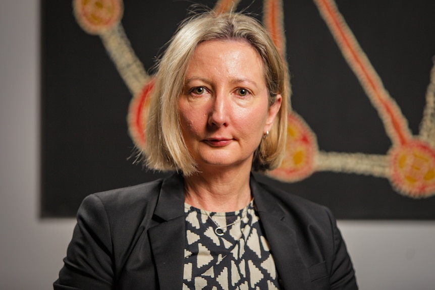 Woman with short blonde hair wearing a black blazer.