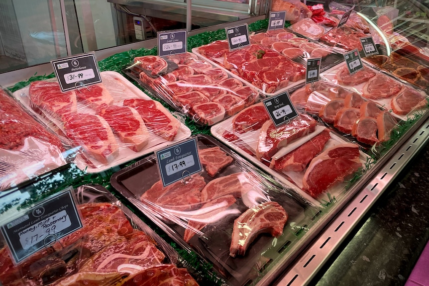 Meat in butcher display with plastic covering it.