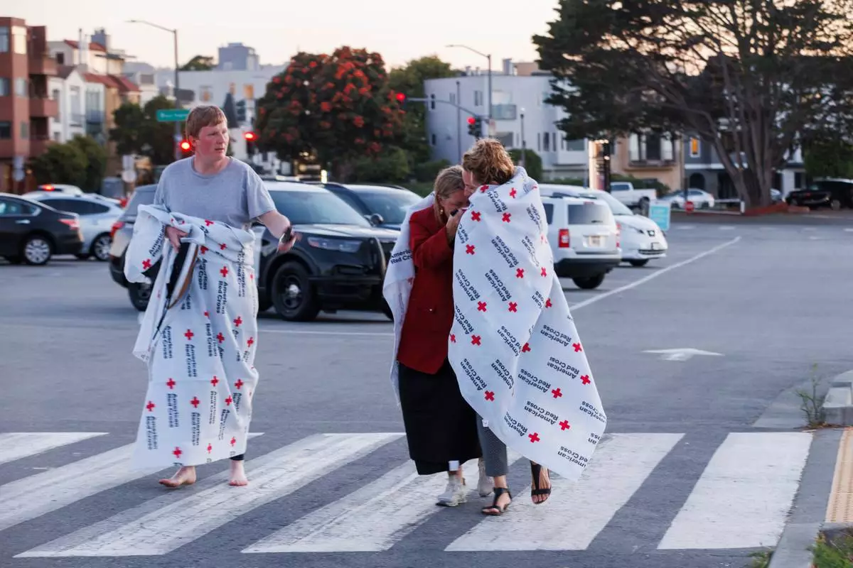 People cover themselves with American Red Cross blankets at Fort Mason, where the Red Cross has set up an assistance center for people impacted by a boat incident in the waters off San Francisco Tuesday, July 14, 2026. (Santiago Mejia/San Francisco Chronicle via AP)