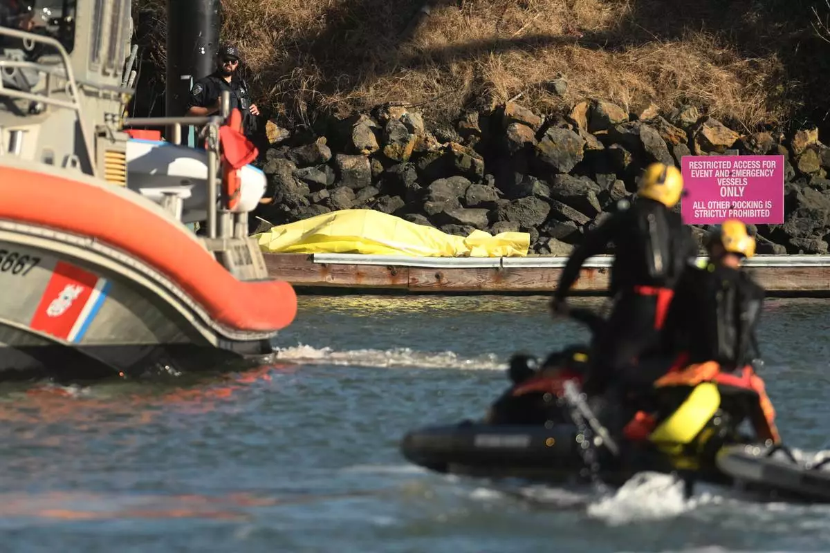 A body is covered with a tarp on a dock near the site of boat accident on Tuesday, July 14, 2026, in San Francisco. (AP Photo/Noah Berger)