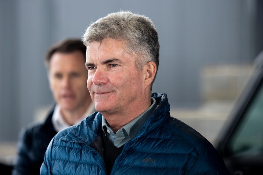 A middle-aged politician stands in front of cameras at a press conference in winter