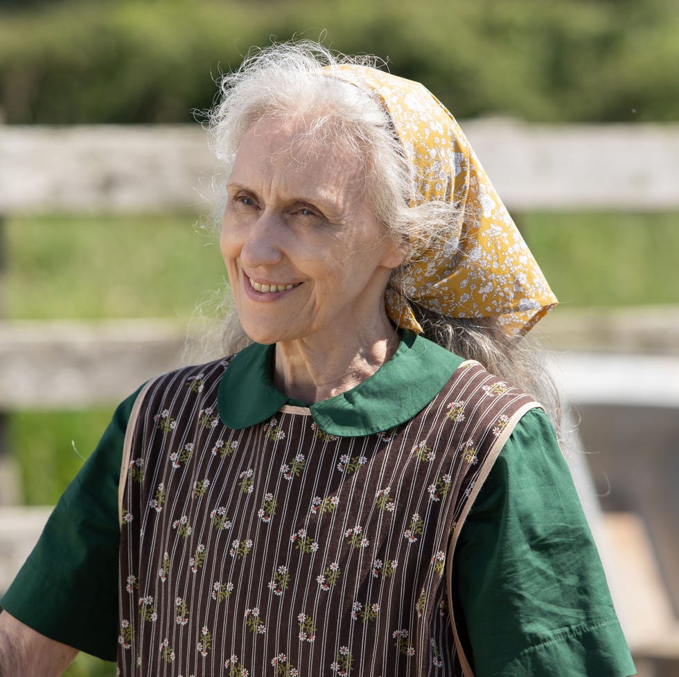 elderly woman wearing traditional clothing in a farm setting