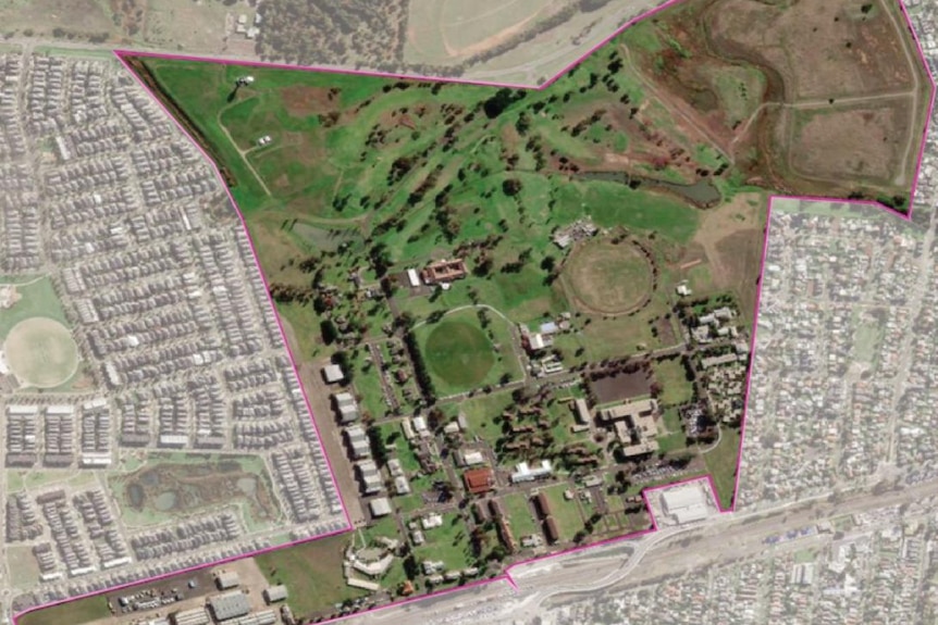 An aerial shot of a propertywith buildings surrounded by ovals and lawn surrounded by a dense surburb.