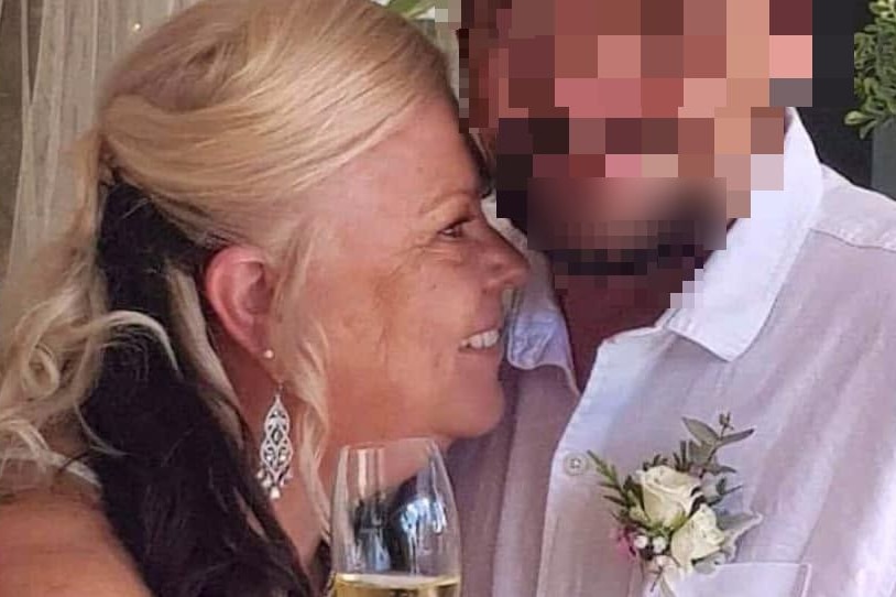 A smiling, older woman with a champagne glass snuggles up to a man, apparently at a wedding.