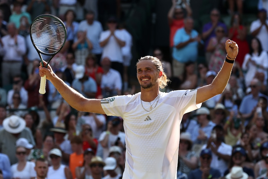 Alexander Zverev raises his arms in celebration holding racquet.