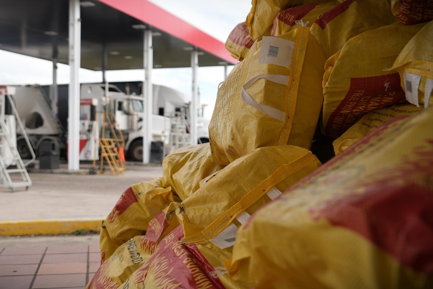 yellow bags of firewood sitting in front of fuel bowser