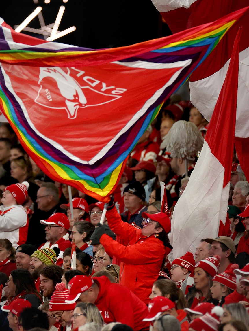 Sydney Swans crowd wave pride flags.