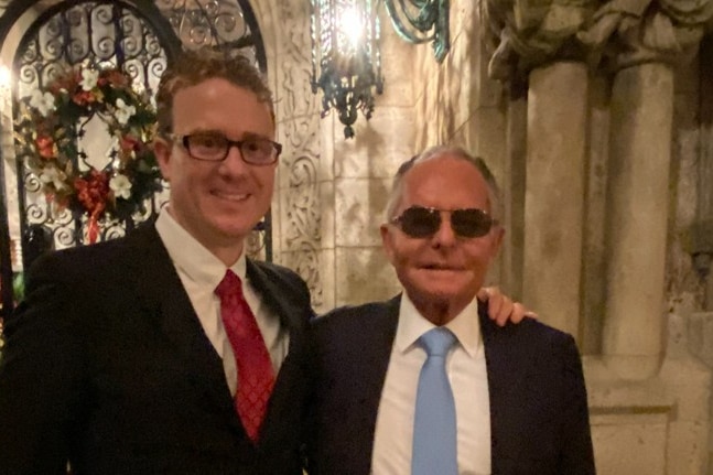 Two men standing beside each other wearing suits.