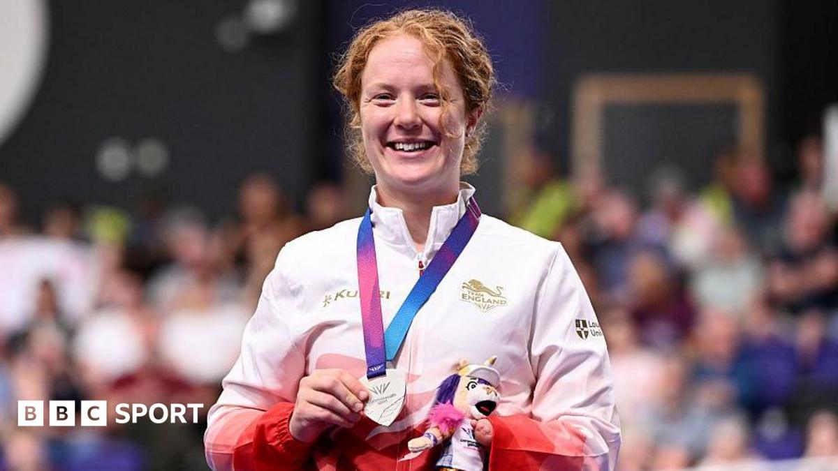 Morgan Newberry stands on the podium with her silver medal in her hand and holding a small mascot toy.