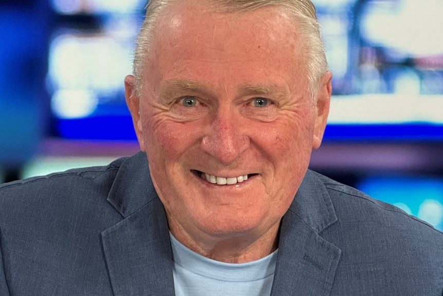 A smiling, middle-aged man in a dark shirt.