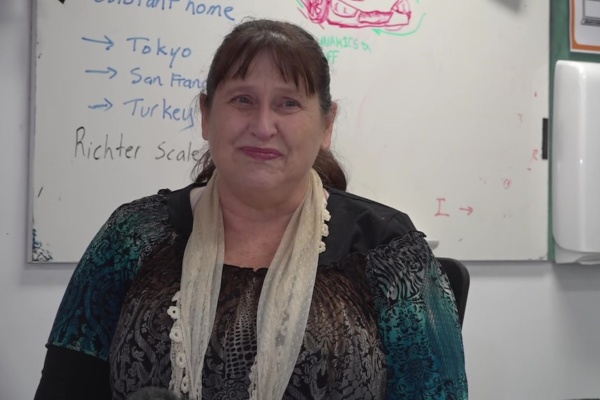 A woman sitting in front of a whiteboard in a science classroom