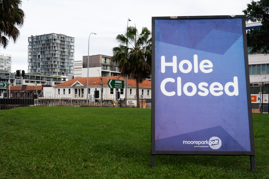 Moore Park golf course with green slopes, hole closed signs, trees and politicians.