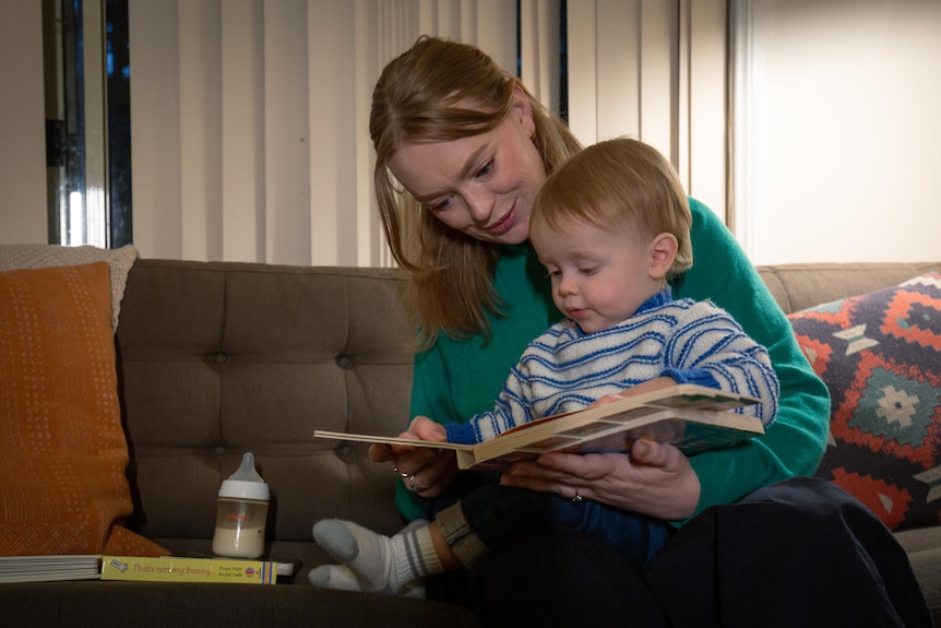 A mother reads to a child sitting on her lap