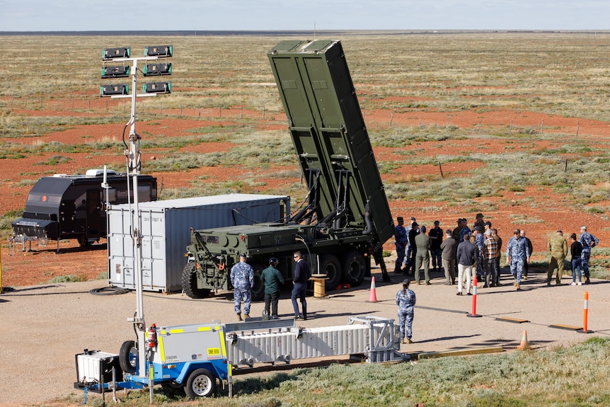 A truck with a missile launch system tilted at almost 90 degrees in an outback area.