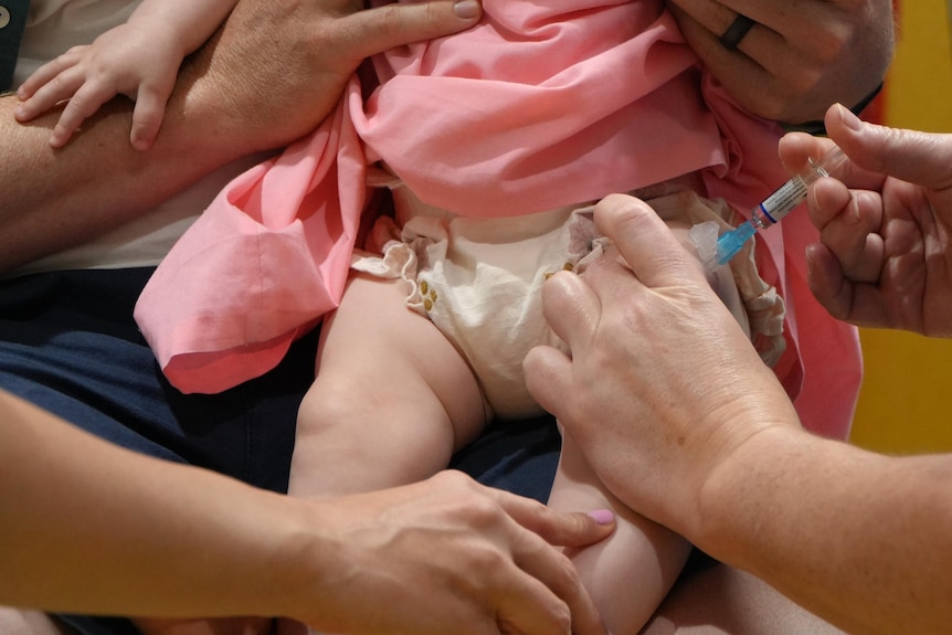 A needle going into a baby's thigh.