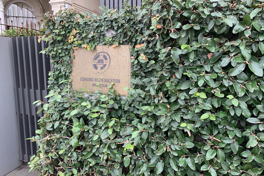 A sign on a fence says "Edmund Rice Education Australia".