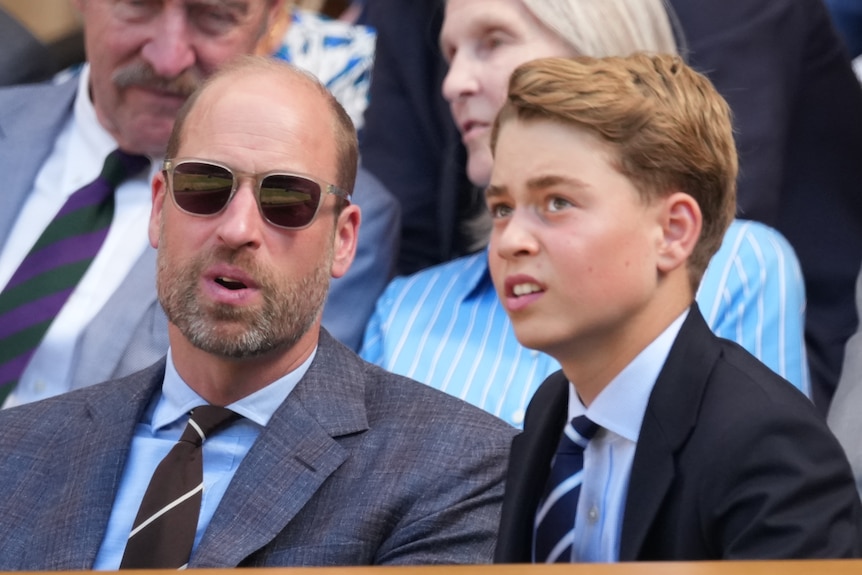 William with sunglasses and George, a young boy, sitting, both wearing suits.