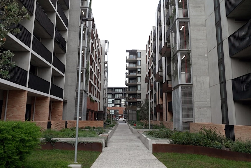 A walkway divides two large modern multi-storey apartment buildings.