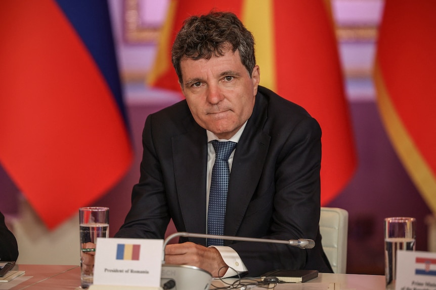 Nicusor Dan leaning forward on a table with a microphone attached.