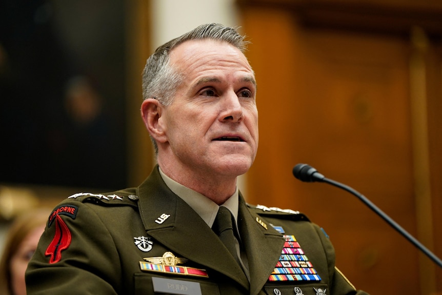 NSA director US Army General Joshua Rudd in his uniform sitting in front of a microphone.