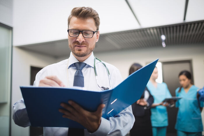 A male doctor reviewing files, representing uncomfortable truths about the medical industry practices.