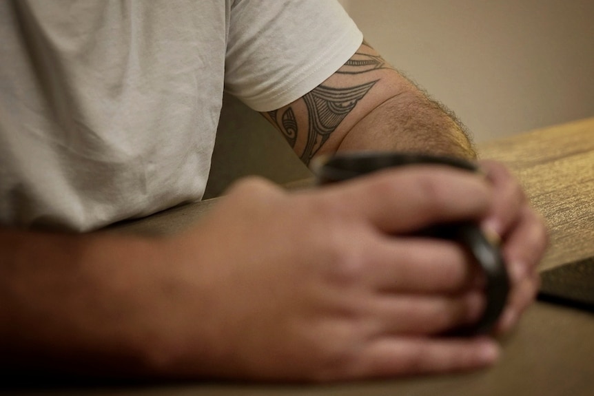 A close-up image of a man's tattooed arms