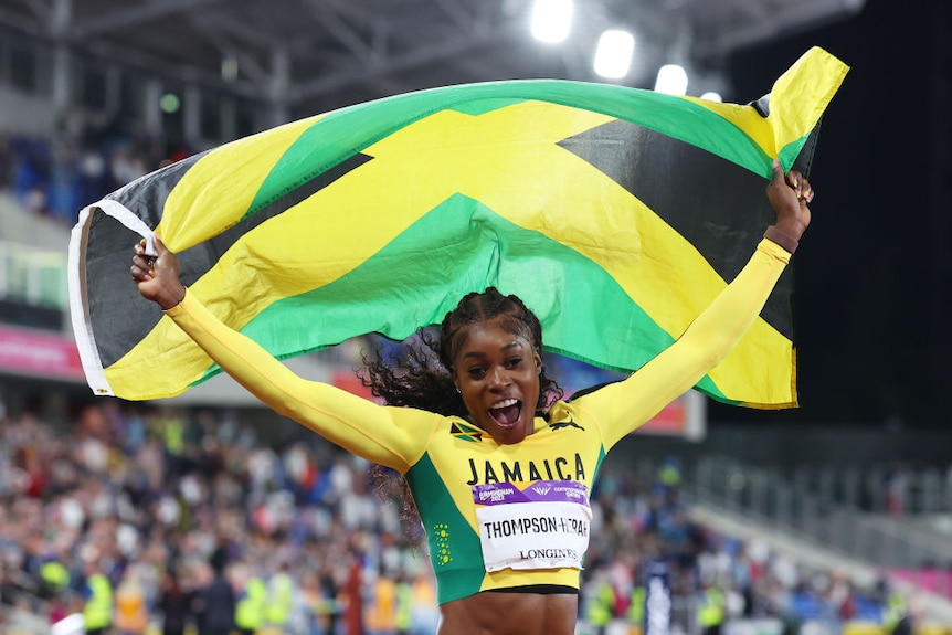 runner Elaine Thompson-Herah waves the jamaican flag above her head