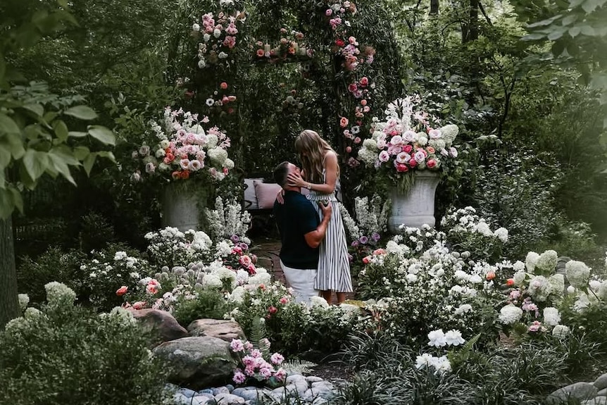 A couple share an embrace in a pretty garden.