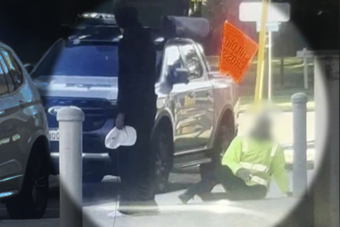 Grainy mobile phone footage of a man laying on the ground while another person stands next to him