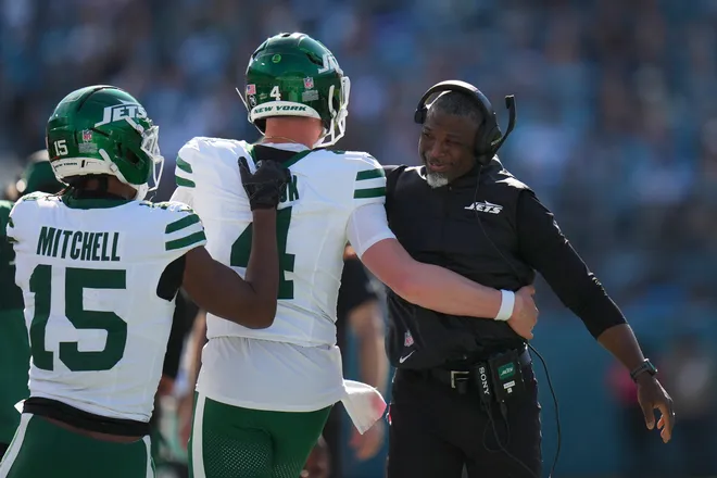JACKSONVILLE, FLORIDA - DECEMBER 14: Head coach Aaron Glenn of the New York Jets celebrates with Brady Cook #4 and Adonai Mitchell #15 during the first quarter against the Jacksonville Jaguars at EverBank Stadium on December 14, 2025 in Jacksonville, Florida. (Photo by Rich Storry/Getty Images)
